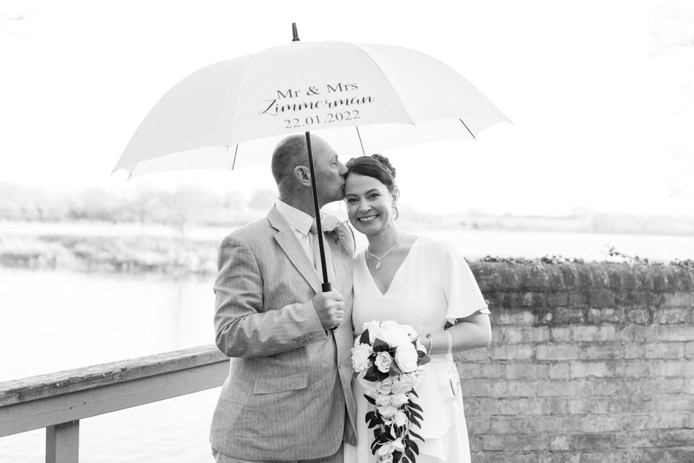 bride and groom pose under an umbrella