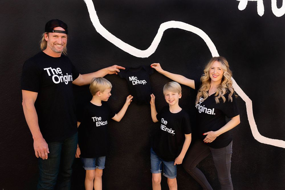 Family photo against black wall with white Texas outline art installation.