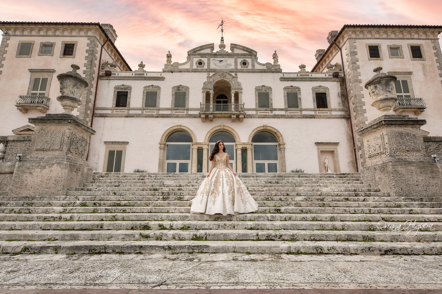 Wedding dress displayed on grand stone steps of historic mansion during sunset.