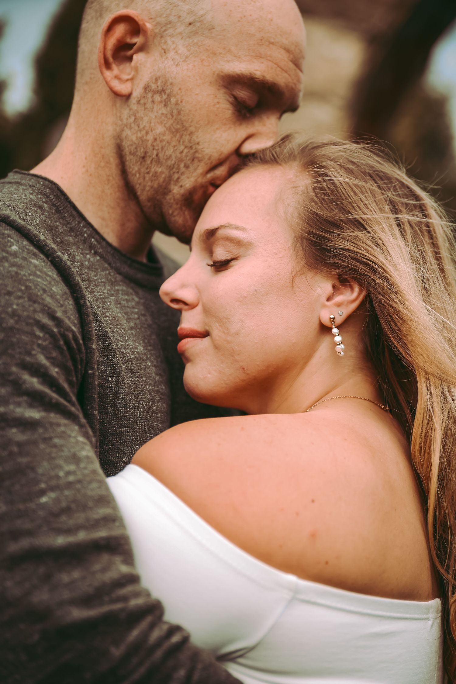 A romantic couple sharing an intimate moment in a close embrace with their eyes closed.