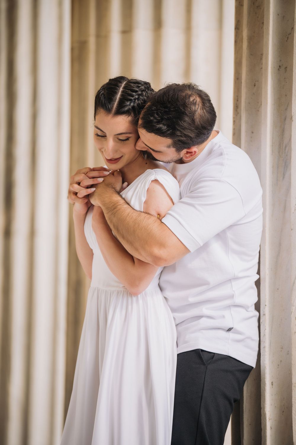 A tender embrace between a couple against a backdrop of elegant curtains, showcasing intimate romance and affection.