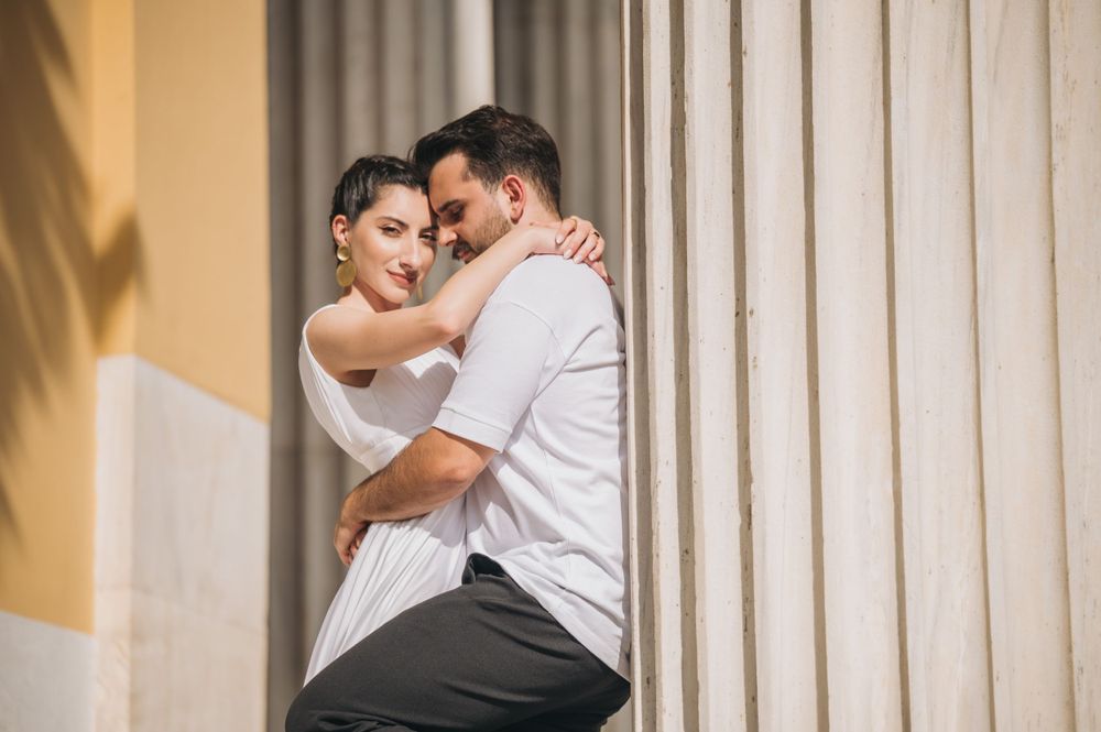 Intimate moment between couple in white and casual wear against architectural columns.