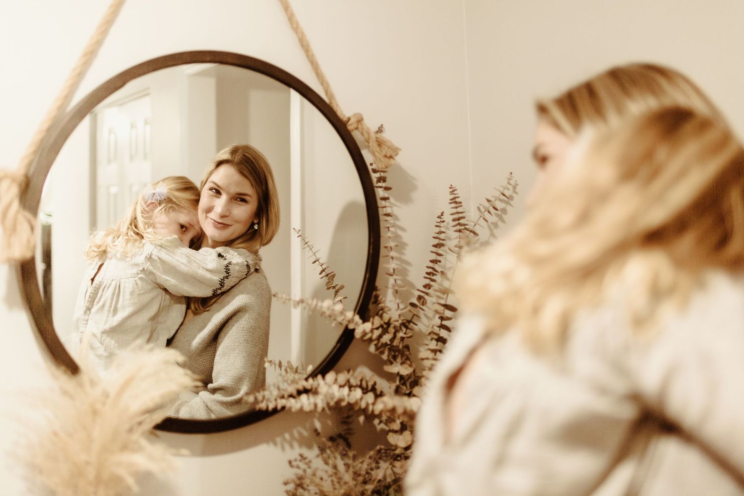 Soft sepia-toned portrait session with circular mirror and eucalyptus decor.