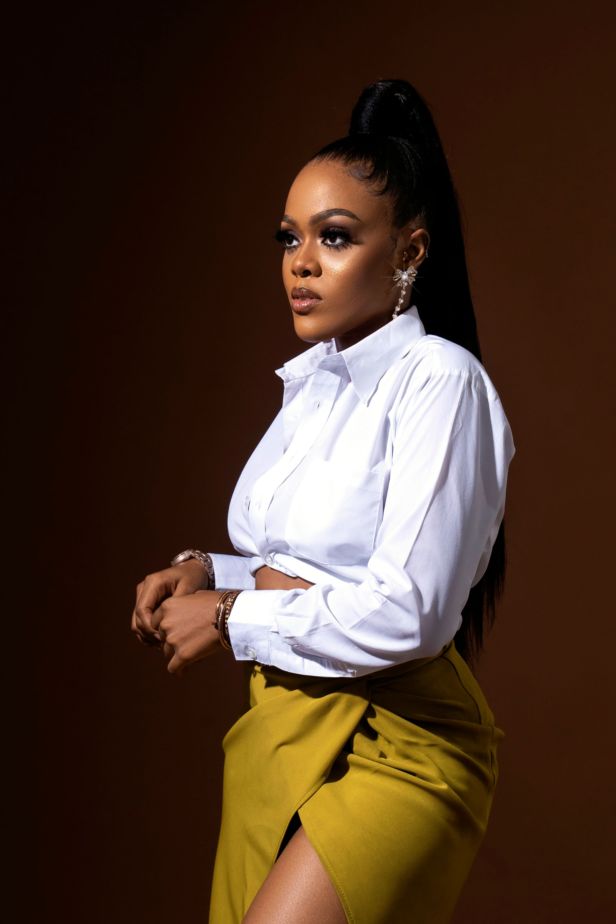 Studio portrait series featuring white button-down shirt and mustard yellow bottom against dark background.