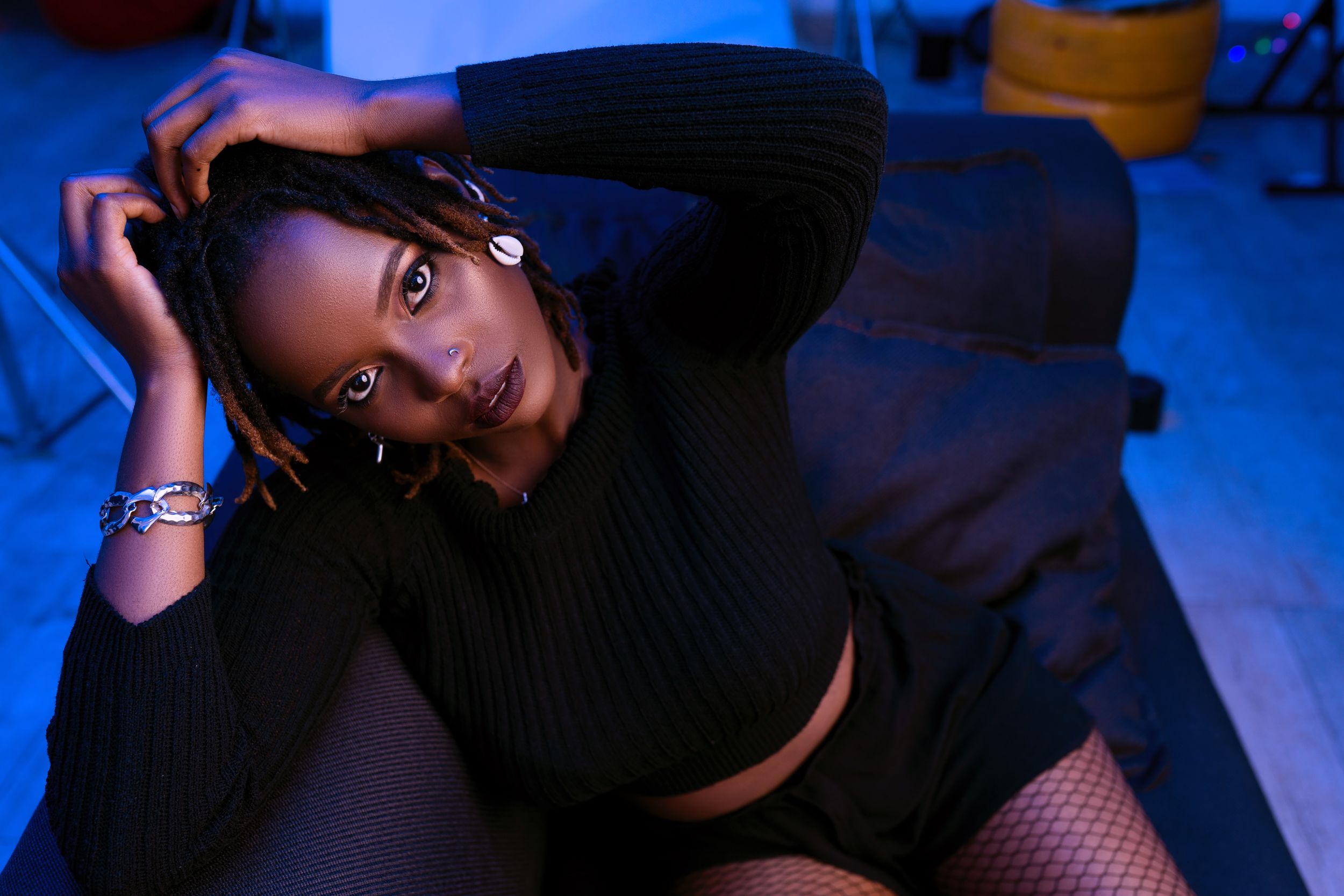 Moody portrait in black sweater with blue lighting on floor.