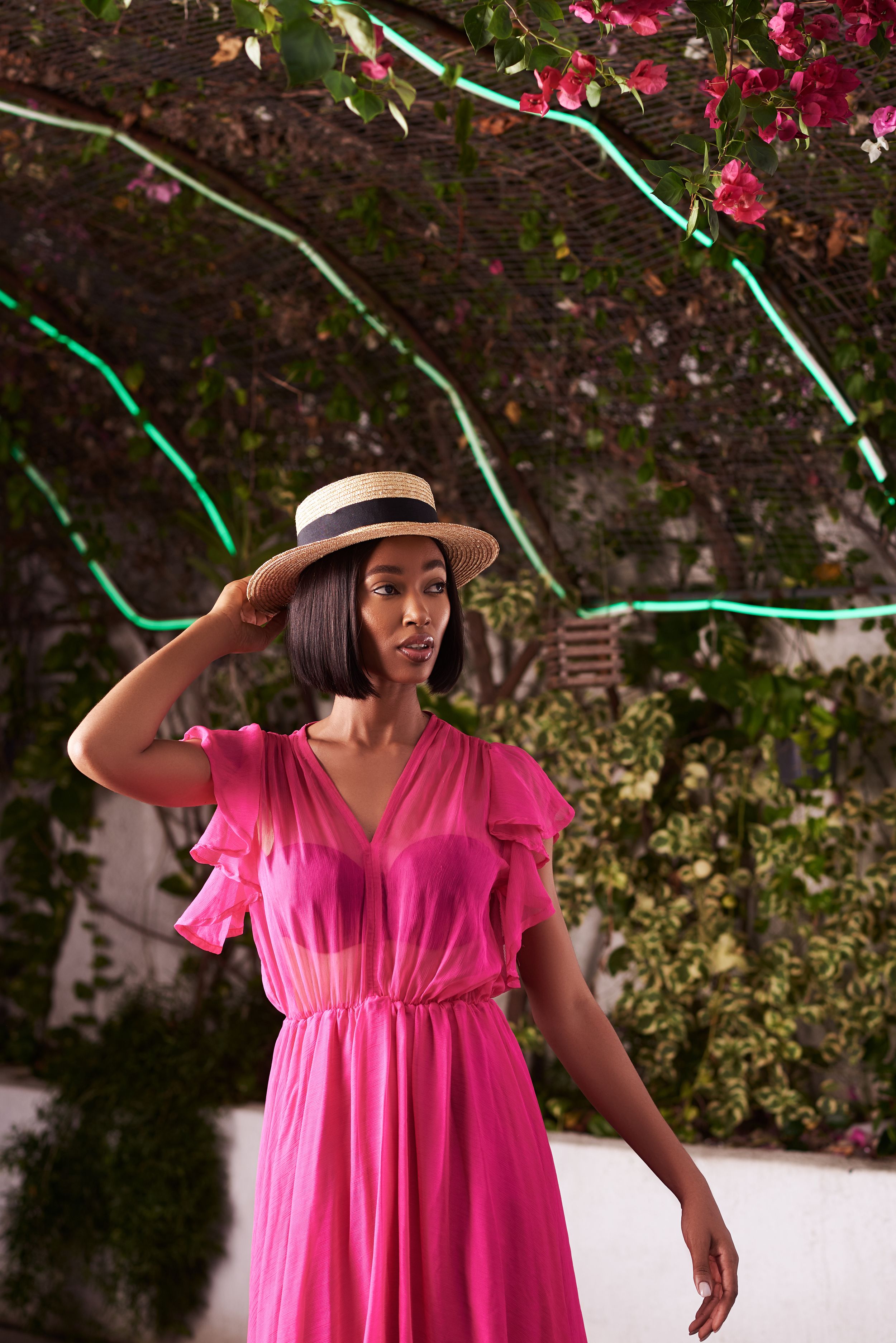 Someone poses in a flowing pink dress in a garden setting with flowers.