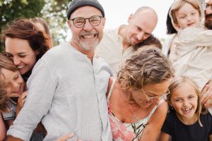 Cheerful extended family sharing laughs during casual outdoor photoshoot.