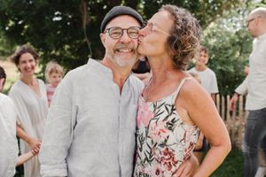 Candid outdoor moment between two people at a casual garden gathering.