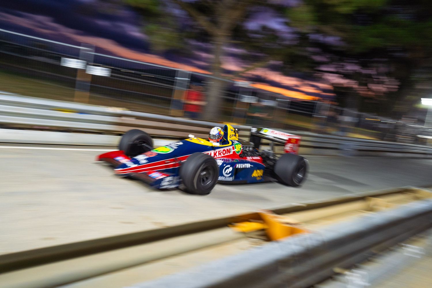 Formula race car speeding past with motion blur effect on a street circuit.