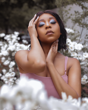 Ethereal beauty shot with soft lighting surrounded by white blossoms in pink top.