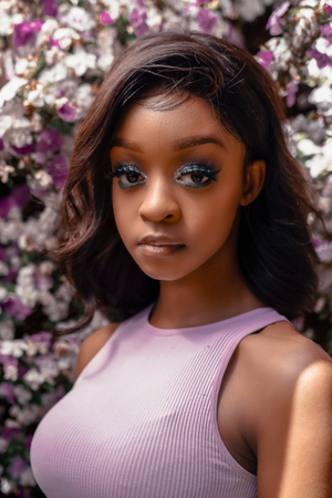 Close-up beauty portrait against blooming spring flowers in lavender attire.