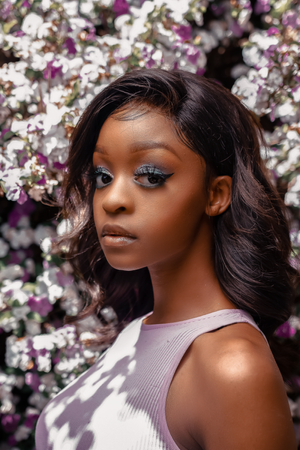 Elegant side profile portrait against purple and white spring blossoms.