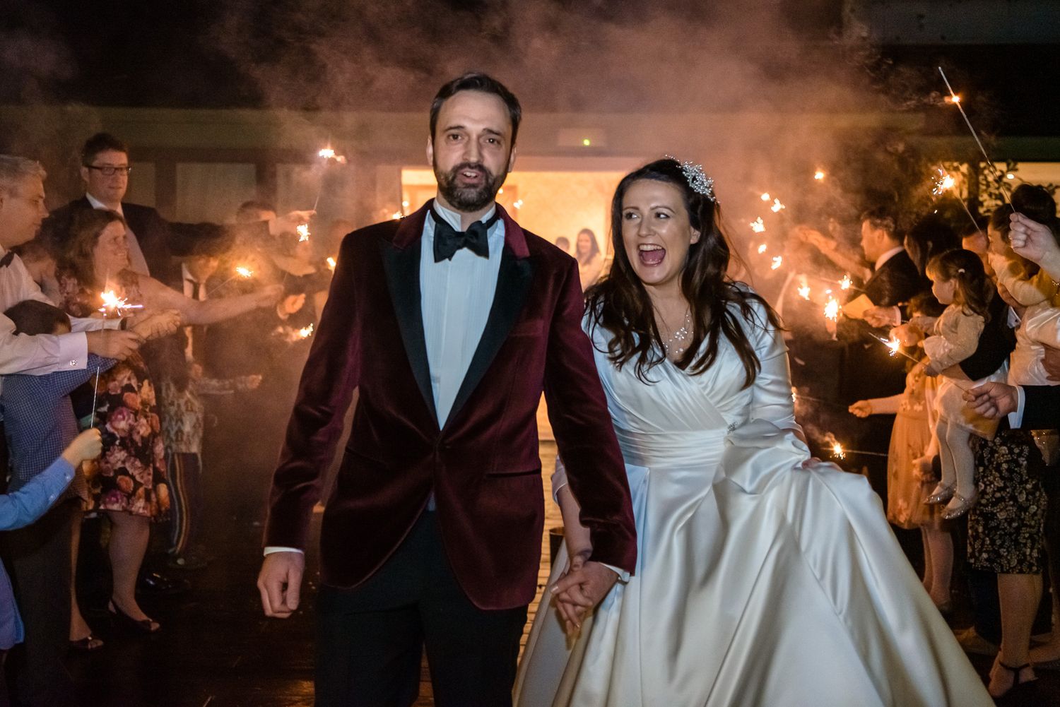 Bride and groom surrounded by guests with sparklers after their Lake District wedding