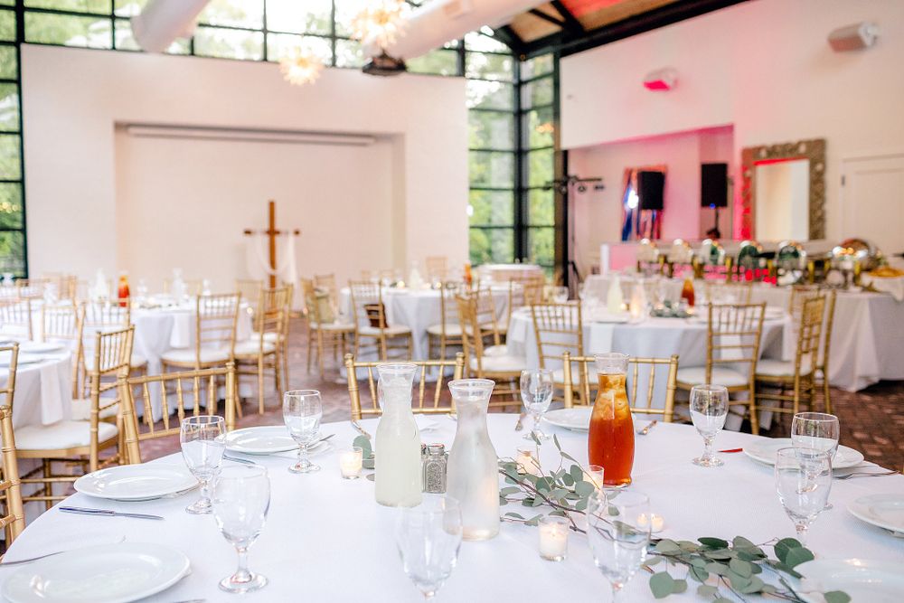 Elegant wedding reception setup with gold chairs and cross detail in bright modern venue.
