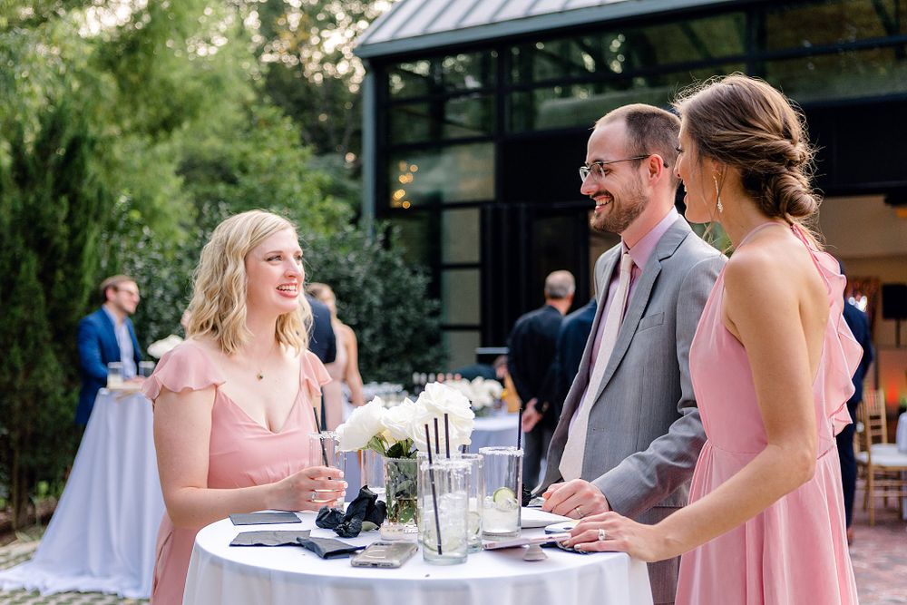 Wedding guests enjoy cocktail hour conversation at outdoor reception.