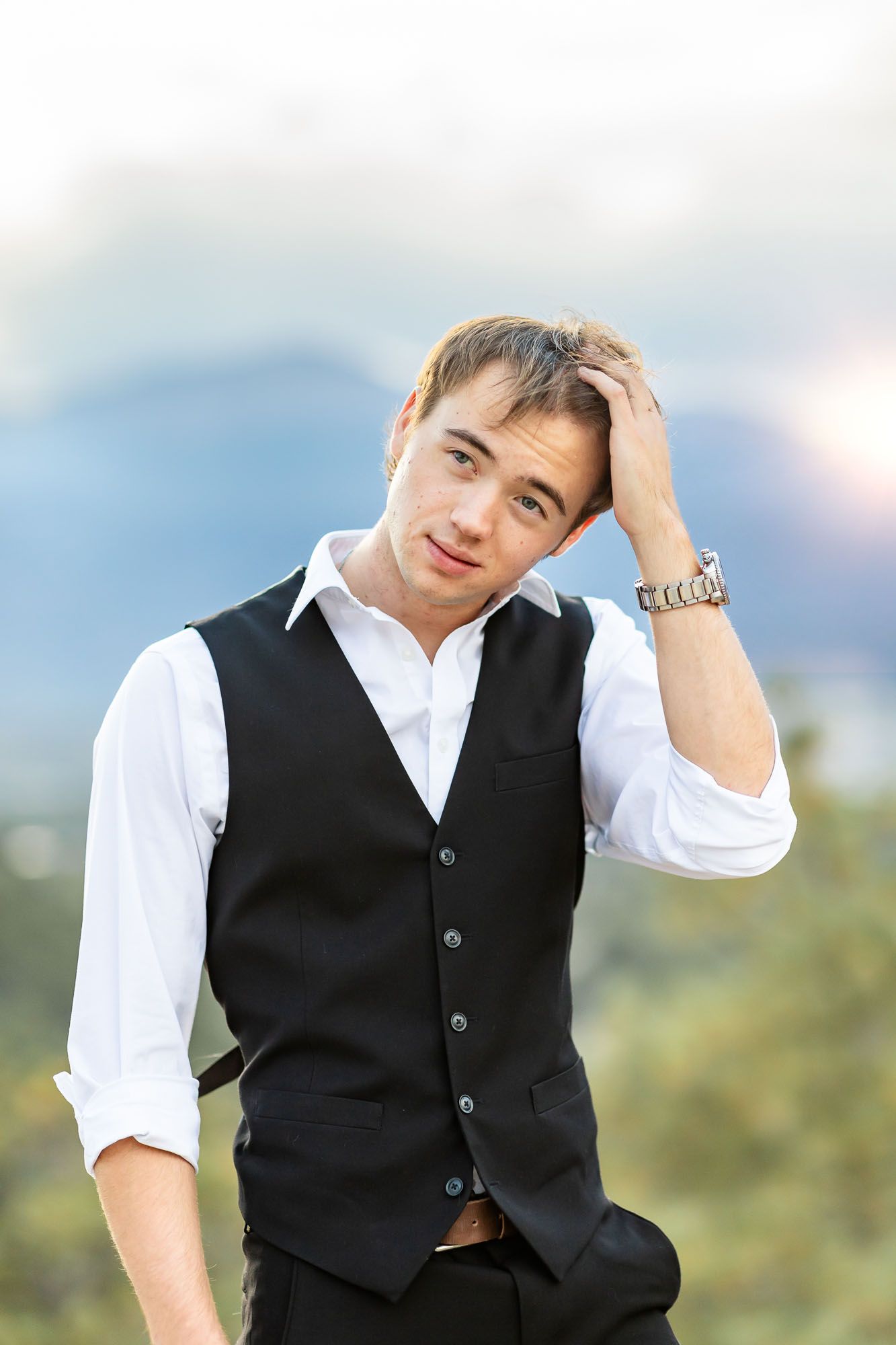 Senior guy runs his hand through his hair and smiles softly to the side at his senior session at Palmer Park in Colorado