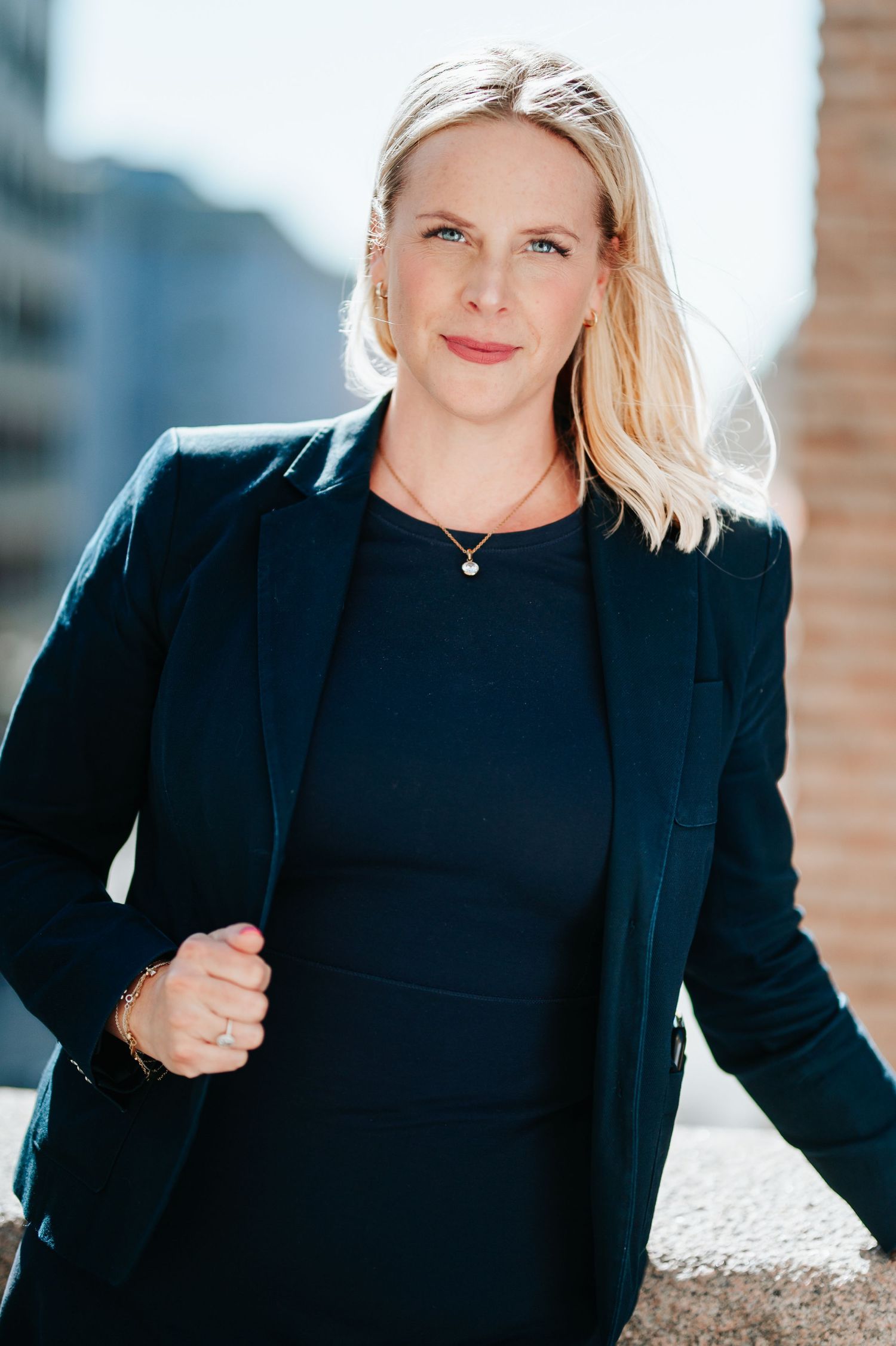 Professional outdoor portrait in a navy business suit with delicate necklace detail.