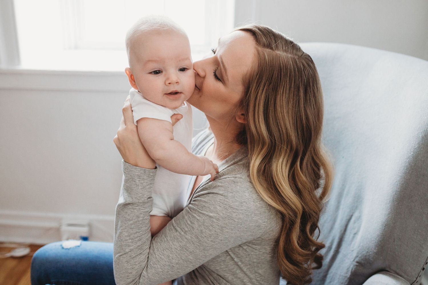A tender moment captured between parent and baby in soft, natural indoor lighting.