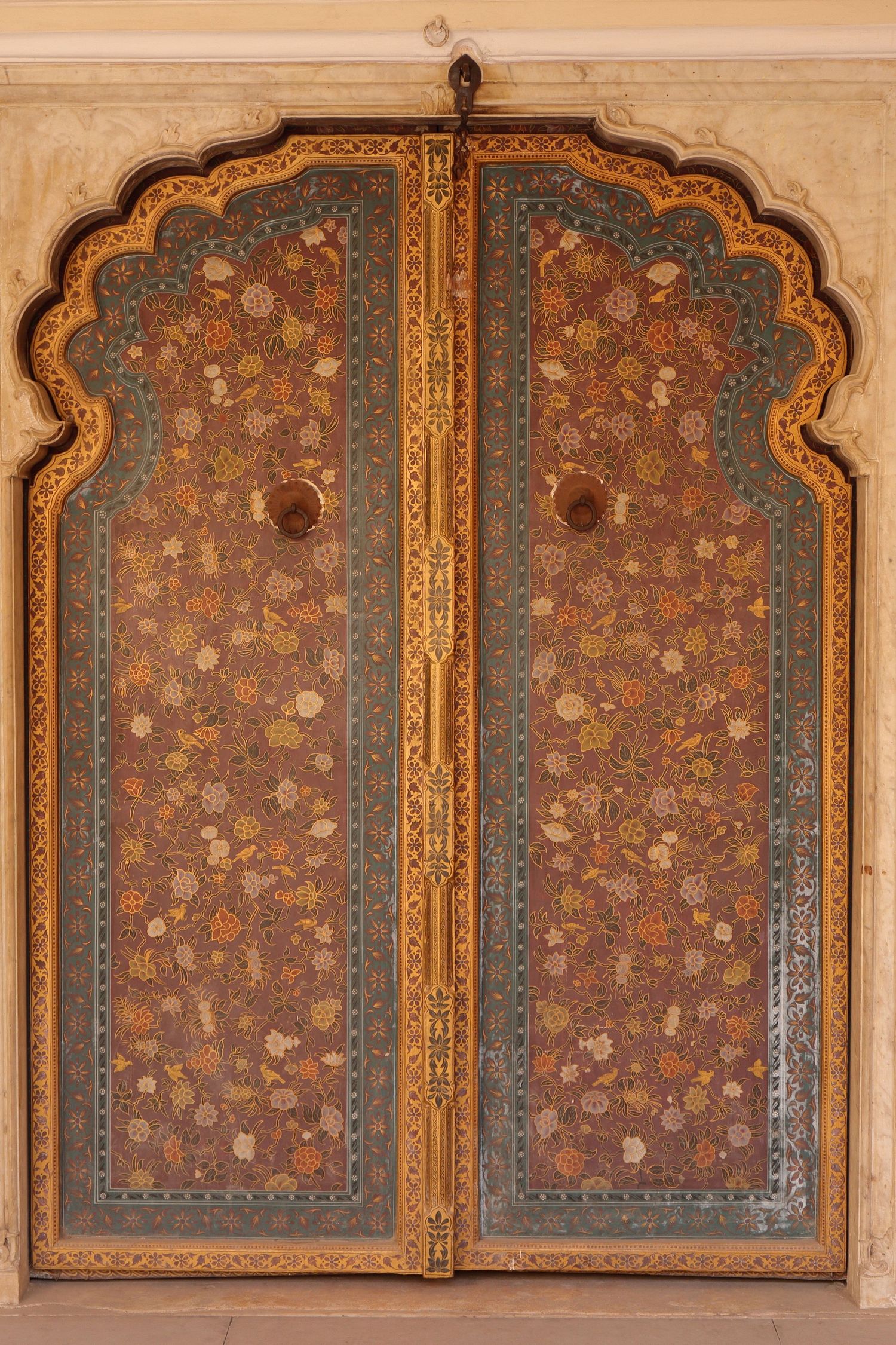 Intricately painted wooden double doors with floral patterns in traditional Indian palace architecture.