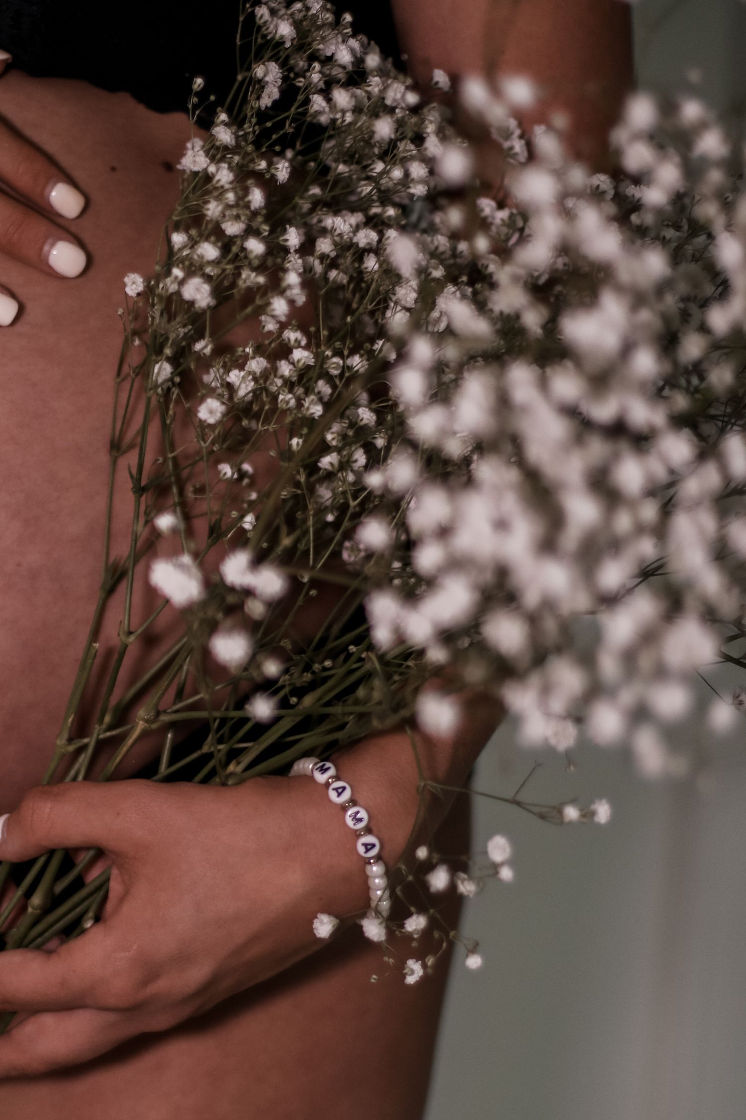Delicate baby's breath flowers held against skin with a dainty bracelet visible.