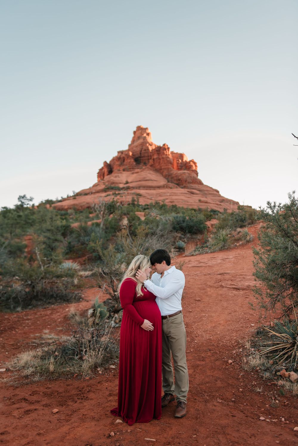 A maternity photoshoot featuring a couple embracing on Sedona's iconic red rock trails.