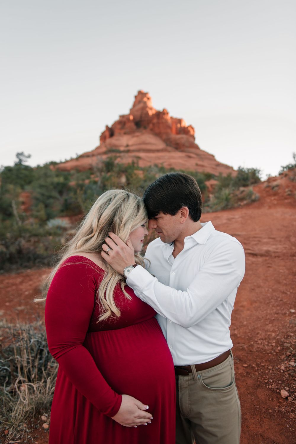 An intimate moment captured between a couple during their maternity session in Sedona's red rocks.