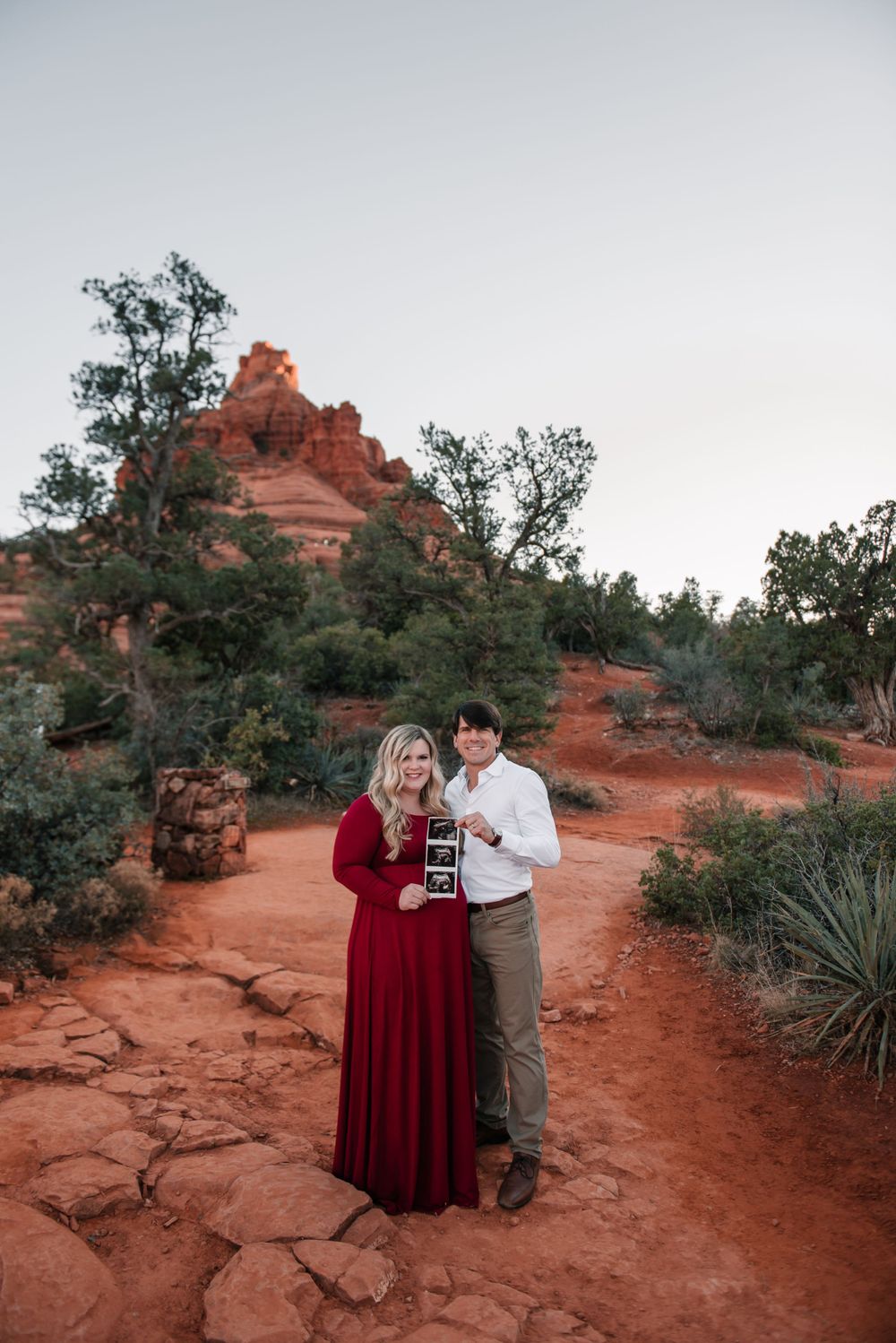 A pregnancy announcement photo session on Sedona's red rock trails at sunset.
