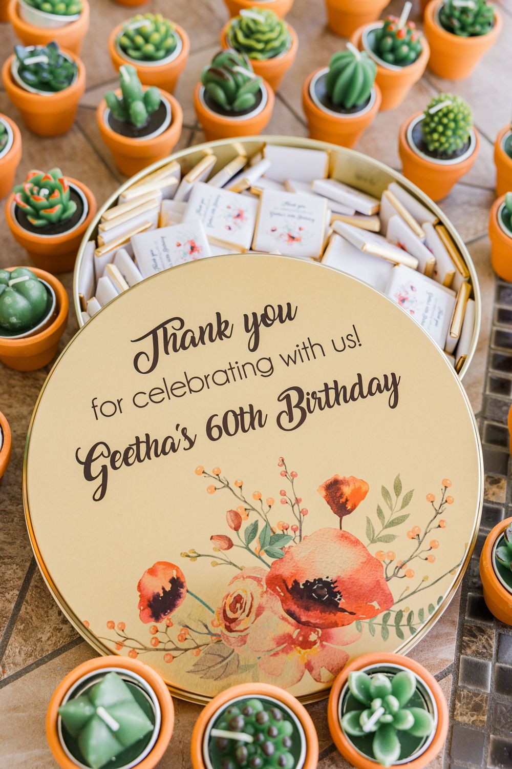 60th birthday thank you sign surrounded by tiny decorative succulent plants in terracotta pots.