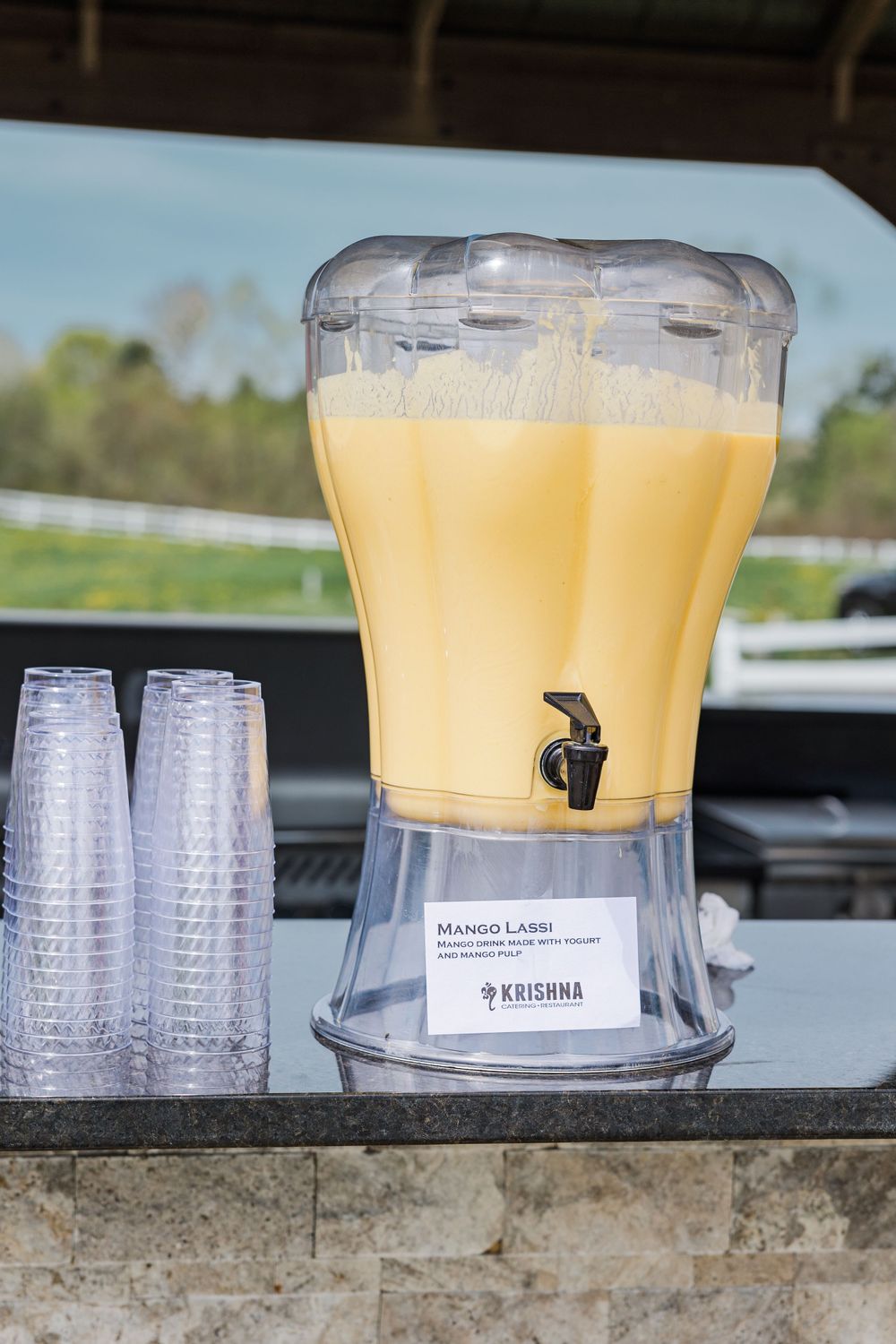 Large beverage dispenser filled with yellow drink and plastic cups.