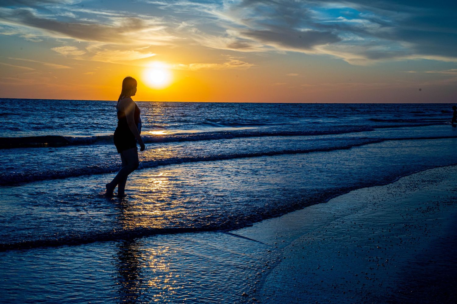 Woman walking along beach at sunset captures the moment