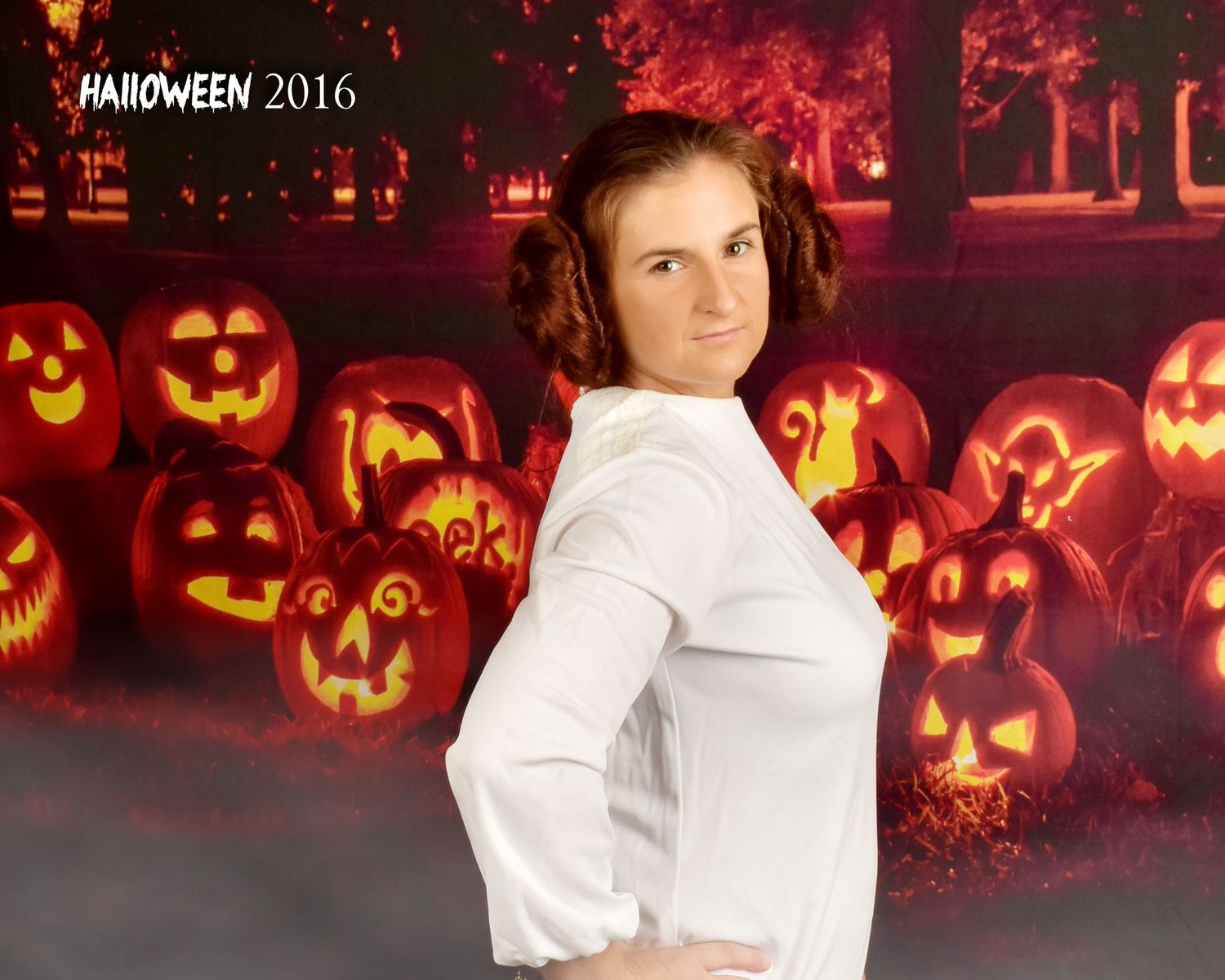 Halloween portrait against glowing orange background with illuminated carved pumpkins.