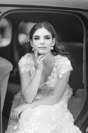 Classic black and white portrait of a bride in a lace gown inside a vintage car.
