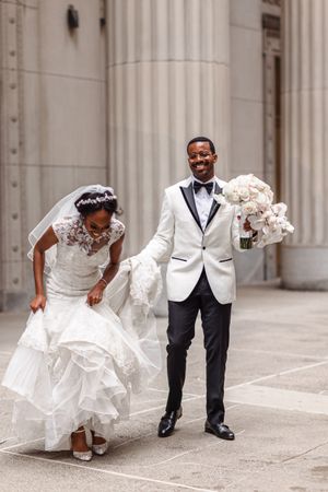 Joyful moment captured outside classic columned building during wedding celebration.