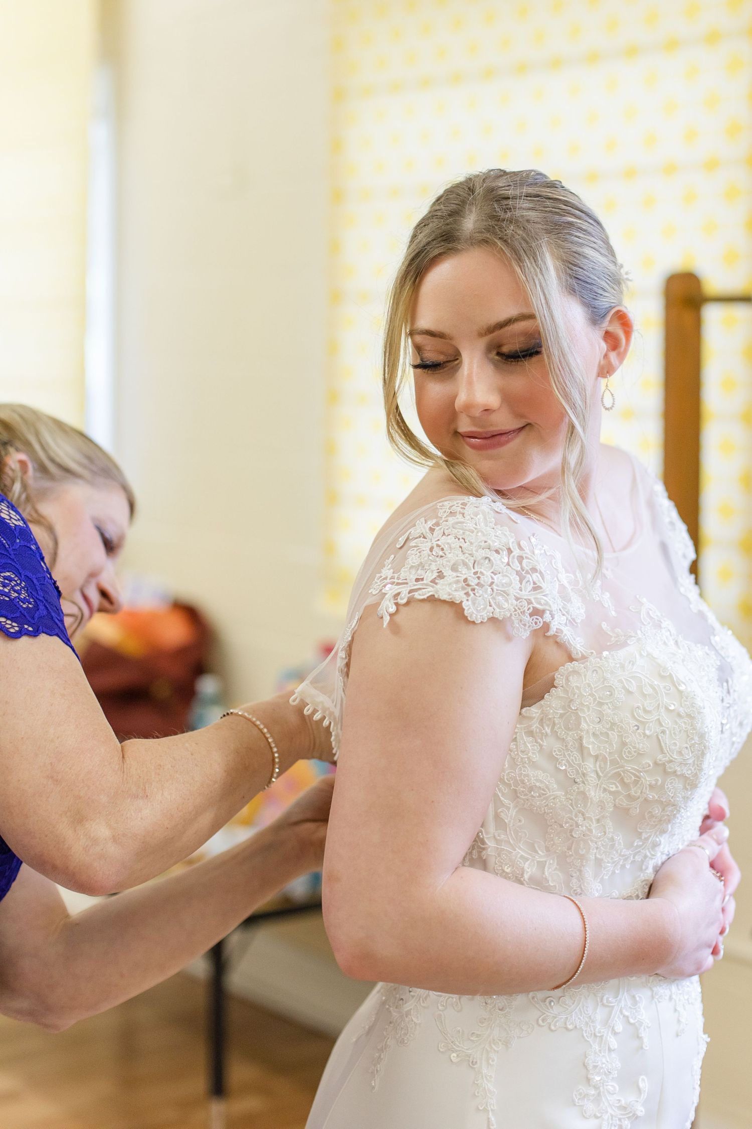 A bride getting help with the final adjustments to her lace wedding dress.