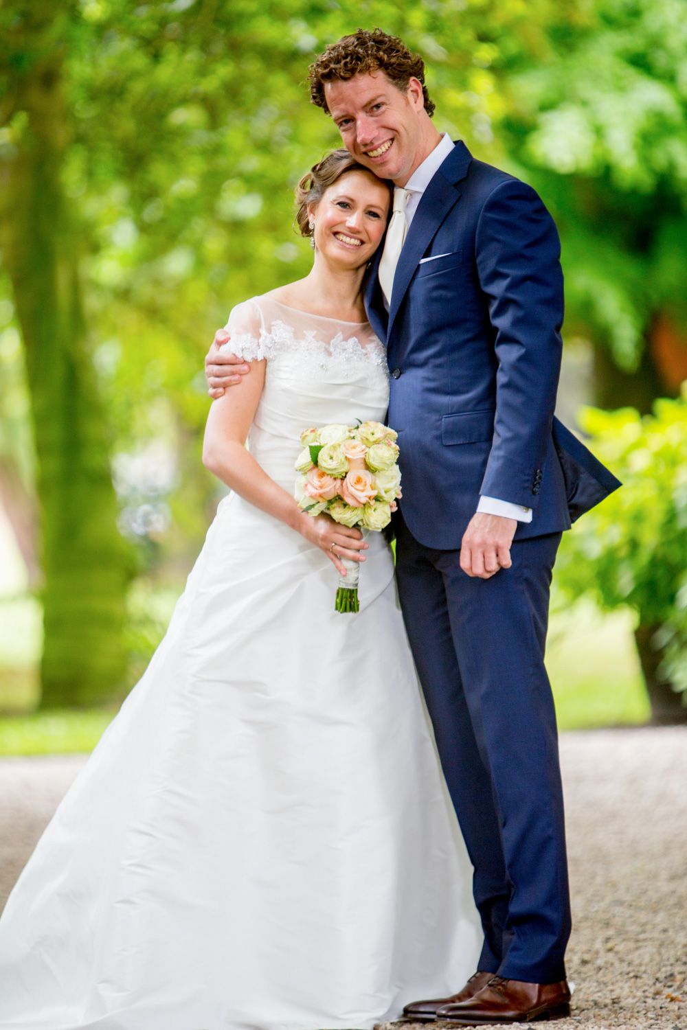Wedding couple poses on a garden path surrounded by lush greenery.