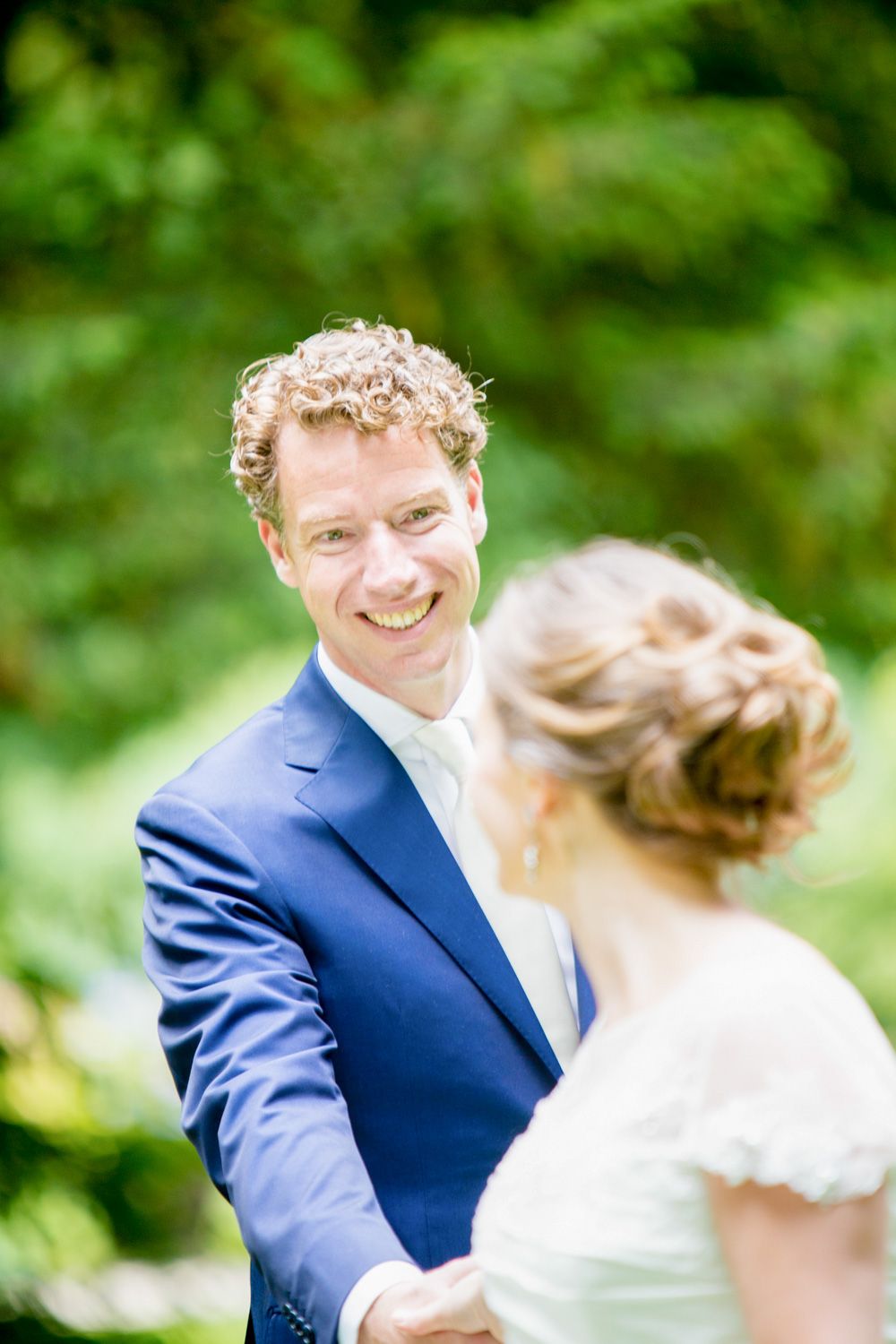 Romantic outdoor wedding photo with vibrant green foliage background.
