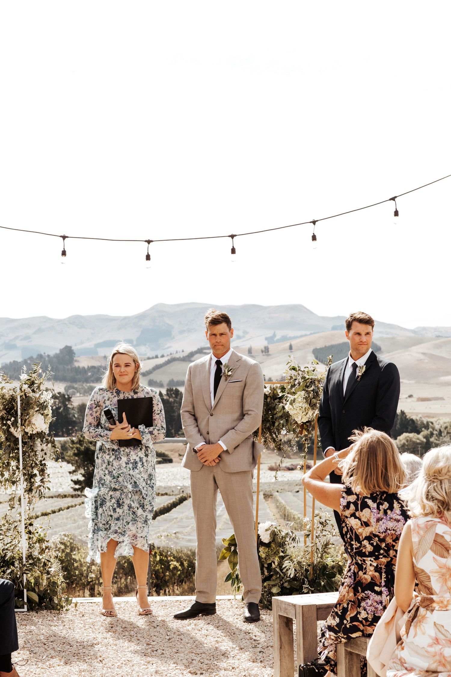 Wedding ceremony setup with string lights and mountain vista backdrop.