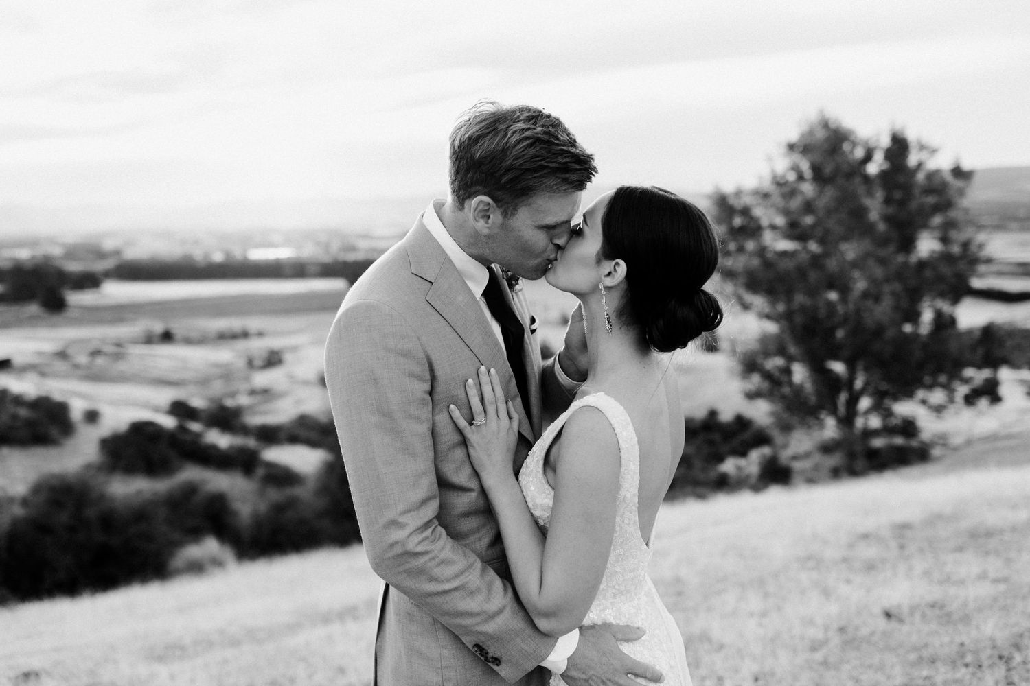 Black and white portrait of newlyweds sharing an intimate moment outdoors.