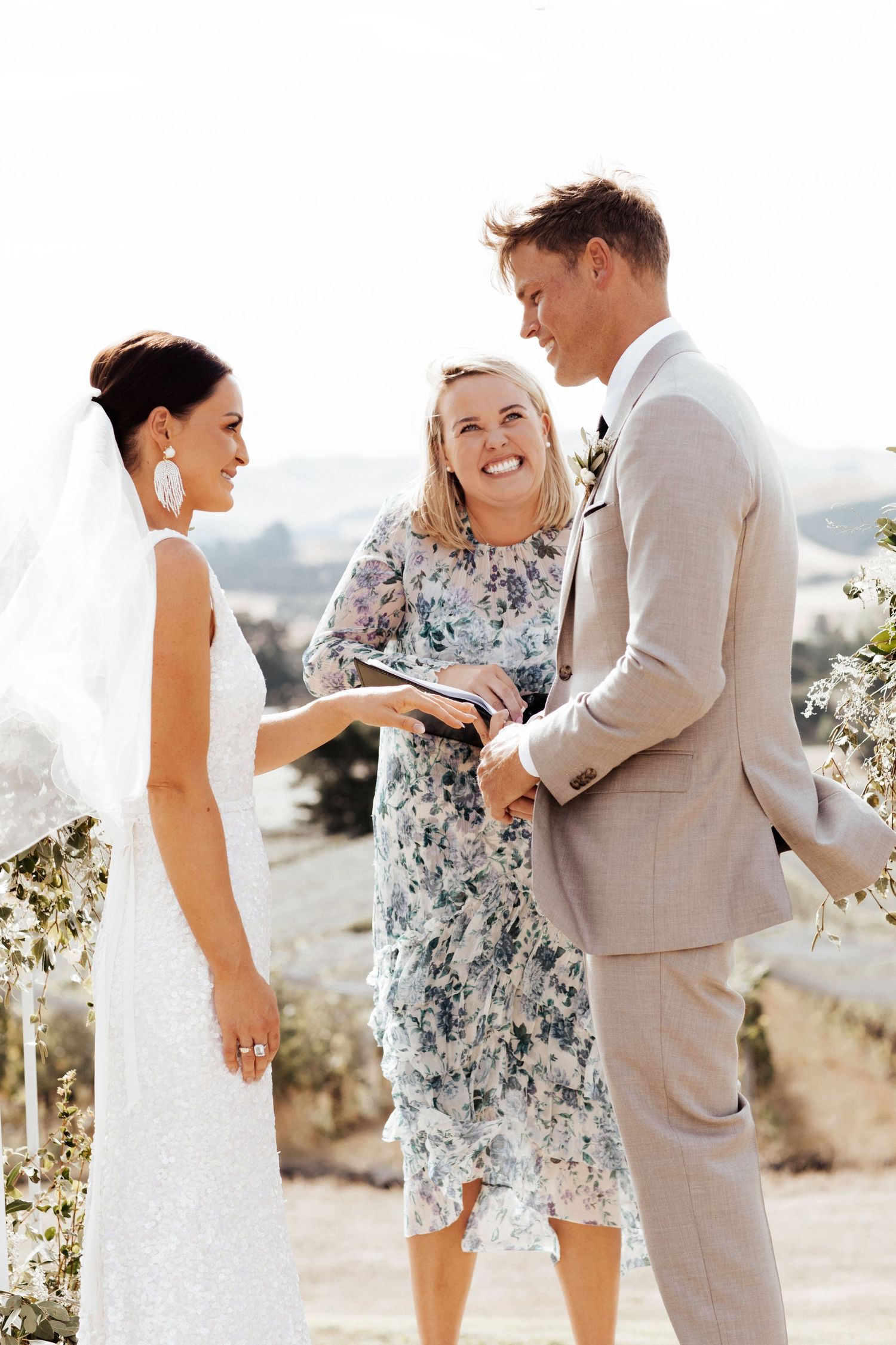 Wedding ceremony participants share a lighthearted moment together outdoors.