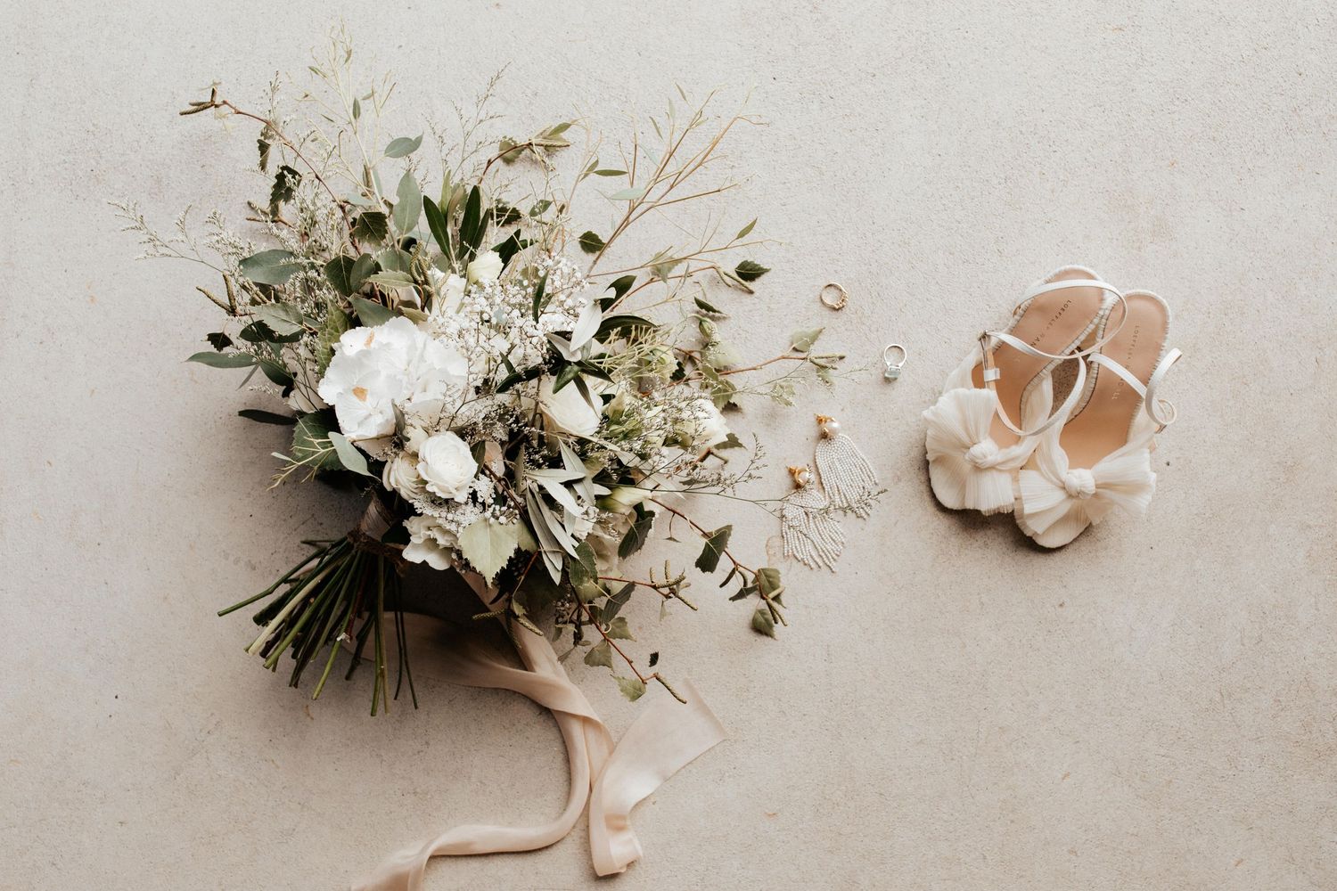 White floral wedding bouquet with eucalyptus leaves next to bridal shoes.