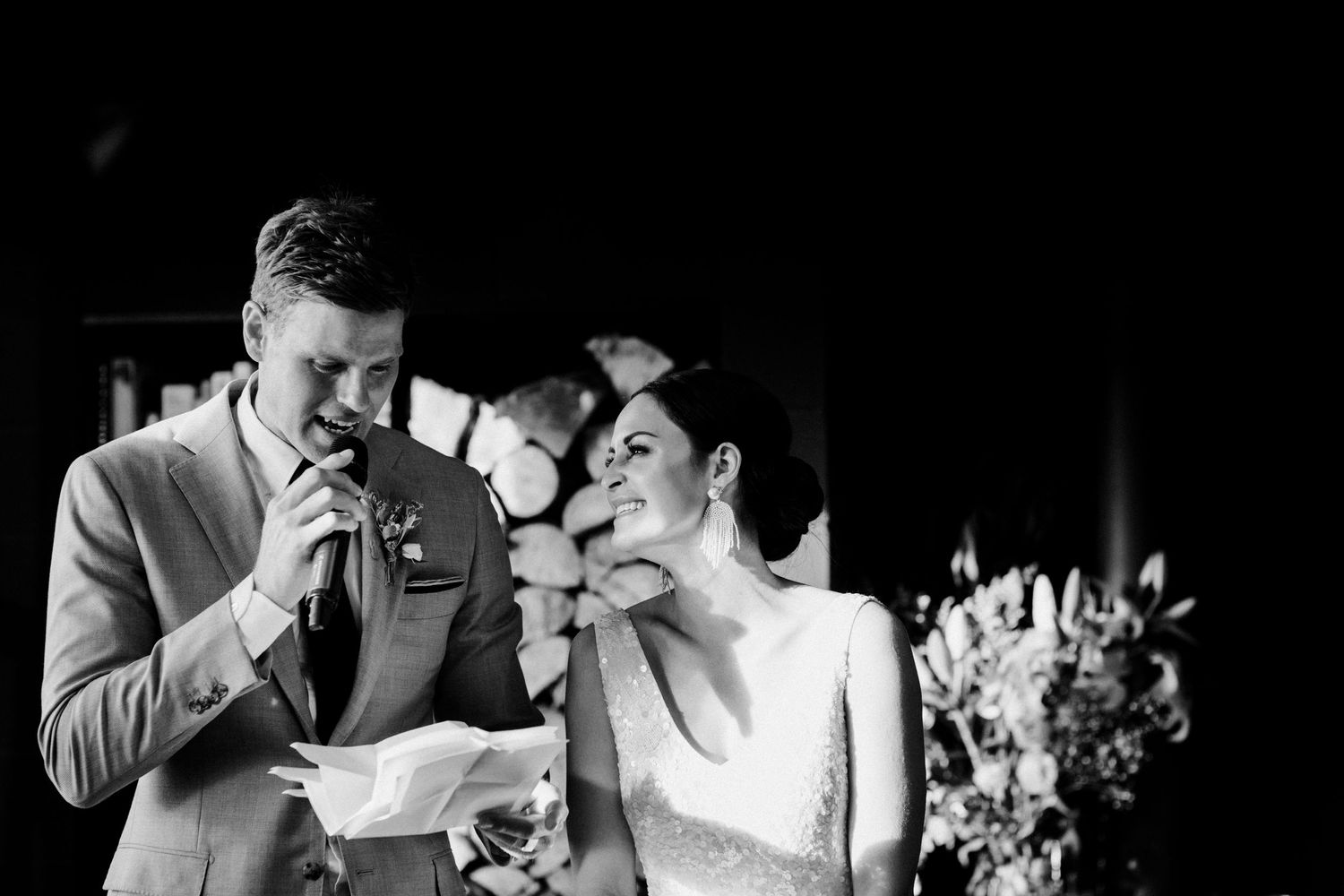 Black and white emotional moment during wedding speech with couple reacting.
