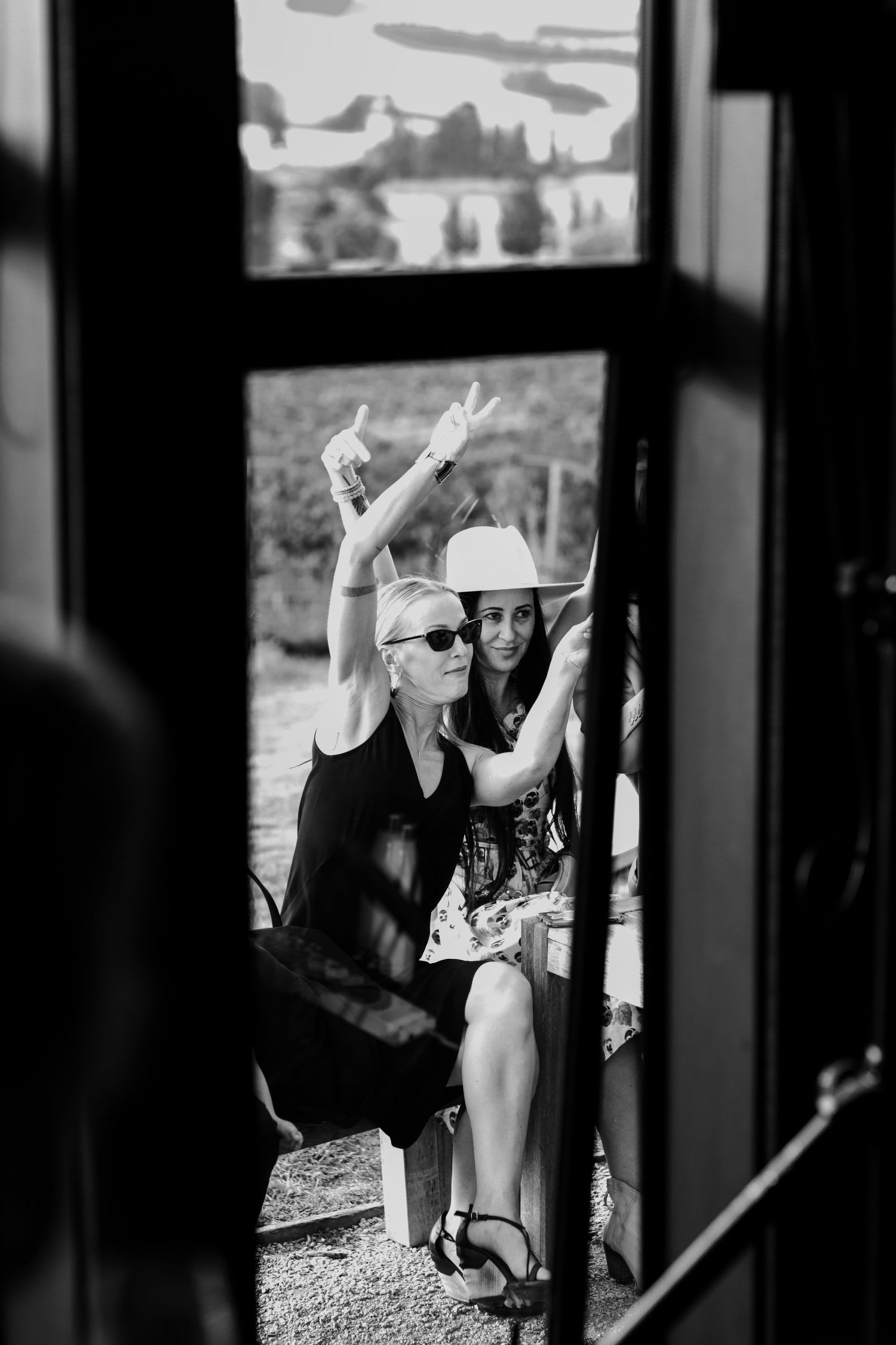Black and white view through window frame of guests celebrating outdoors.