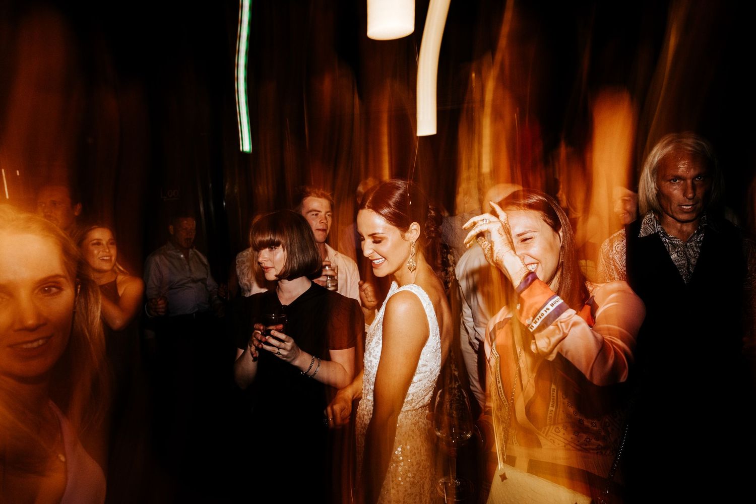 Wedding celebration with moody lighting and motion blur capturing the dance floor atmosphere.