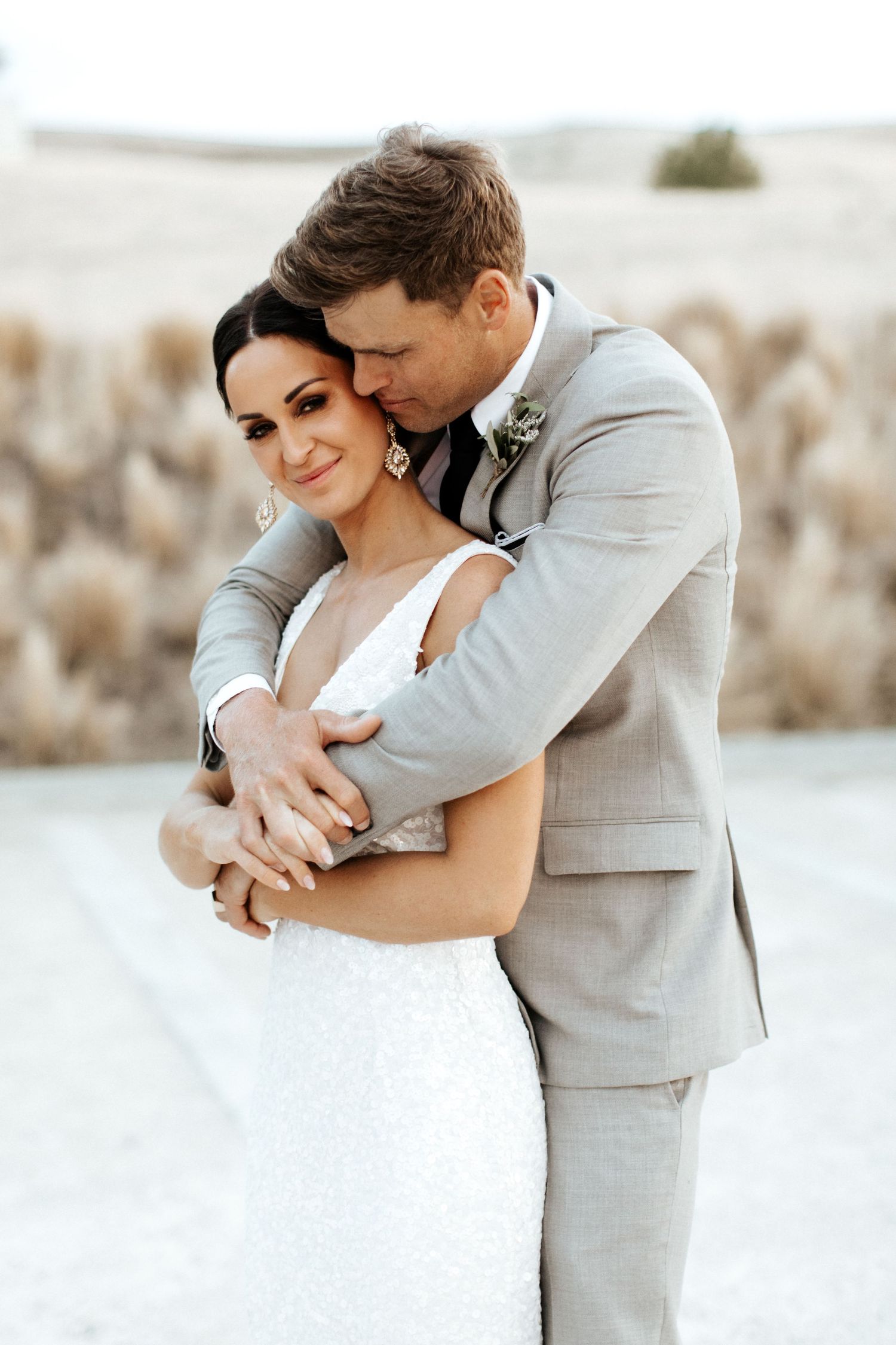 A tender wedding moment captured as newlyweds embrace in an outdoor setting.
