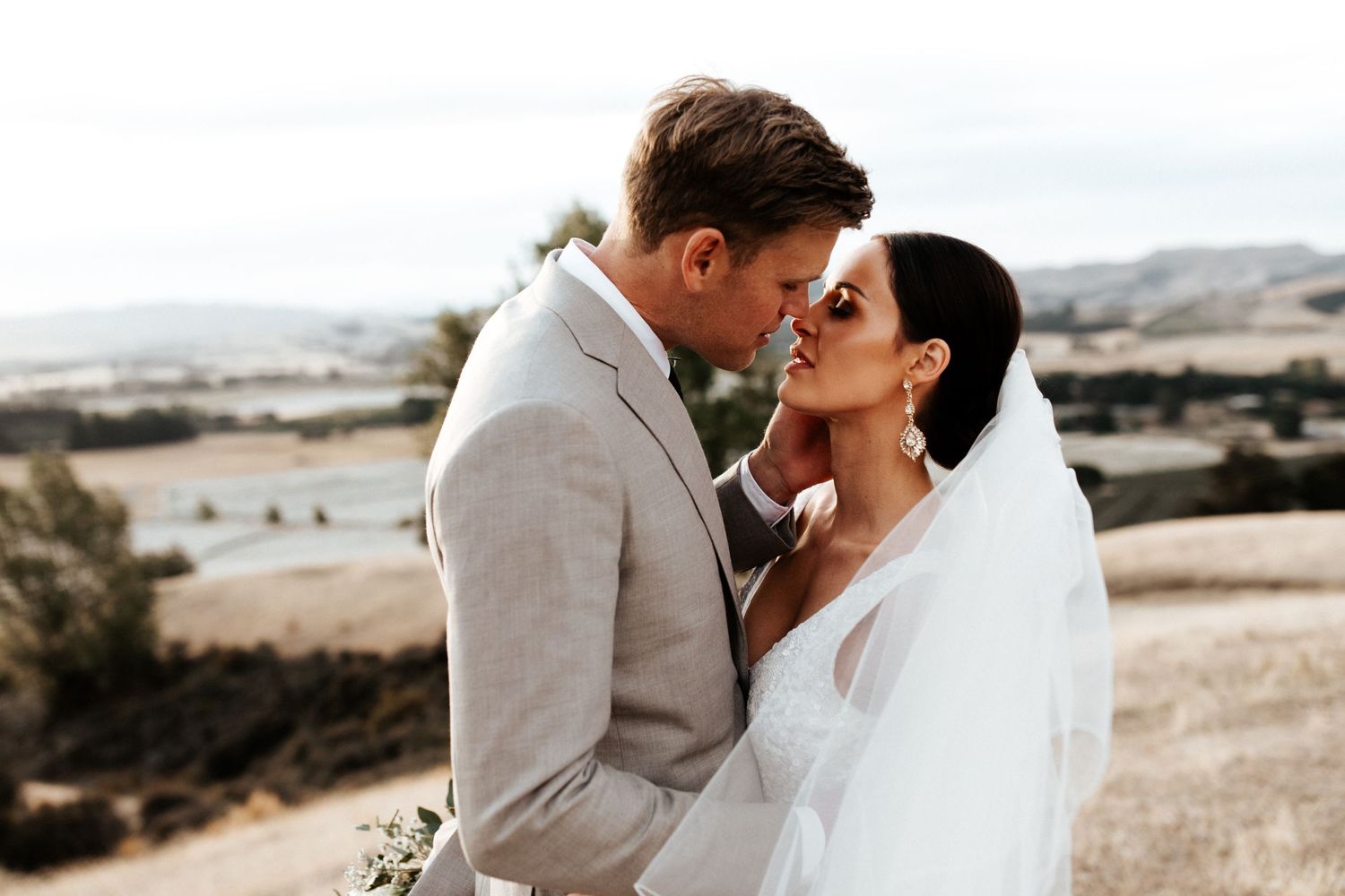 Intimate moment between newlyweds against backdrop of rolling countryside.