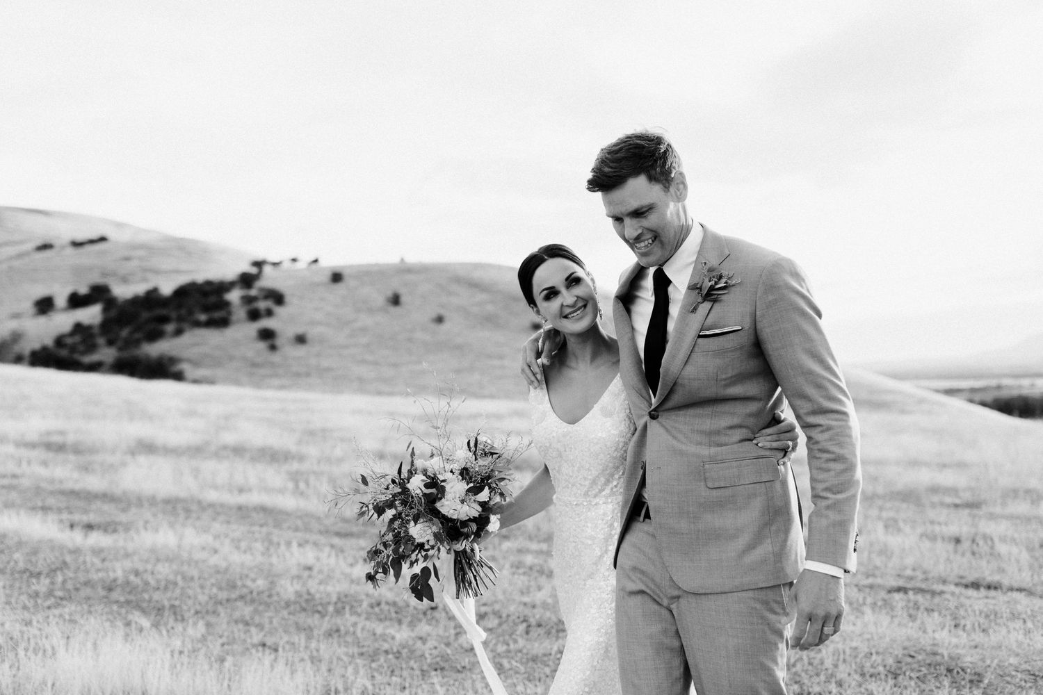 Black and white candid moment of couple laughing together during their outdoor wedding photoshoot.