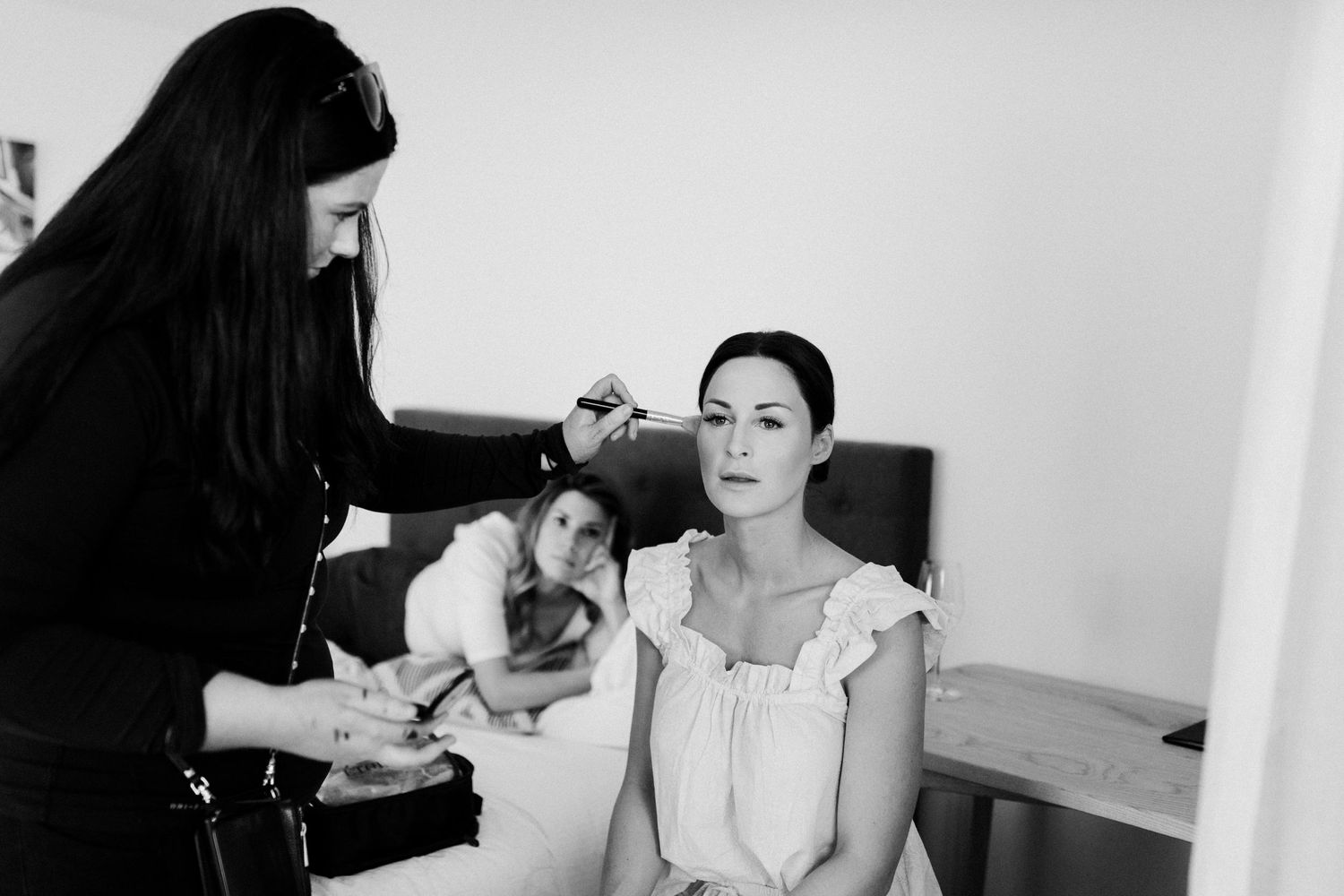 A makeup artist working on bridal preparations in black and white.