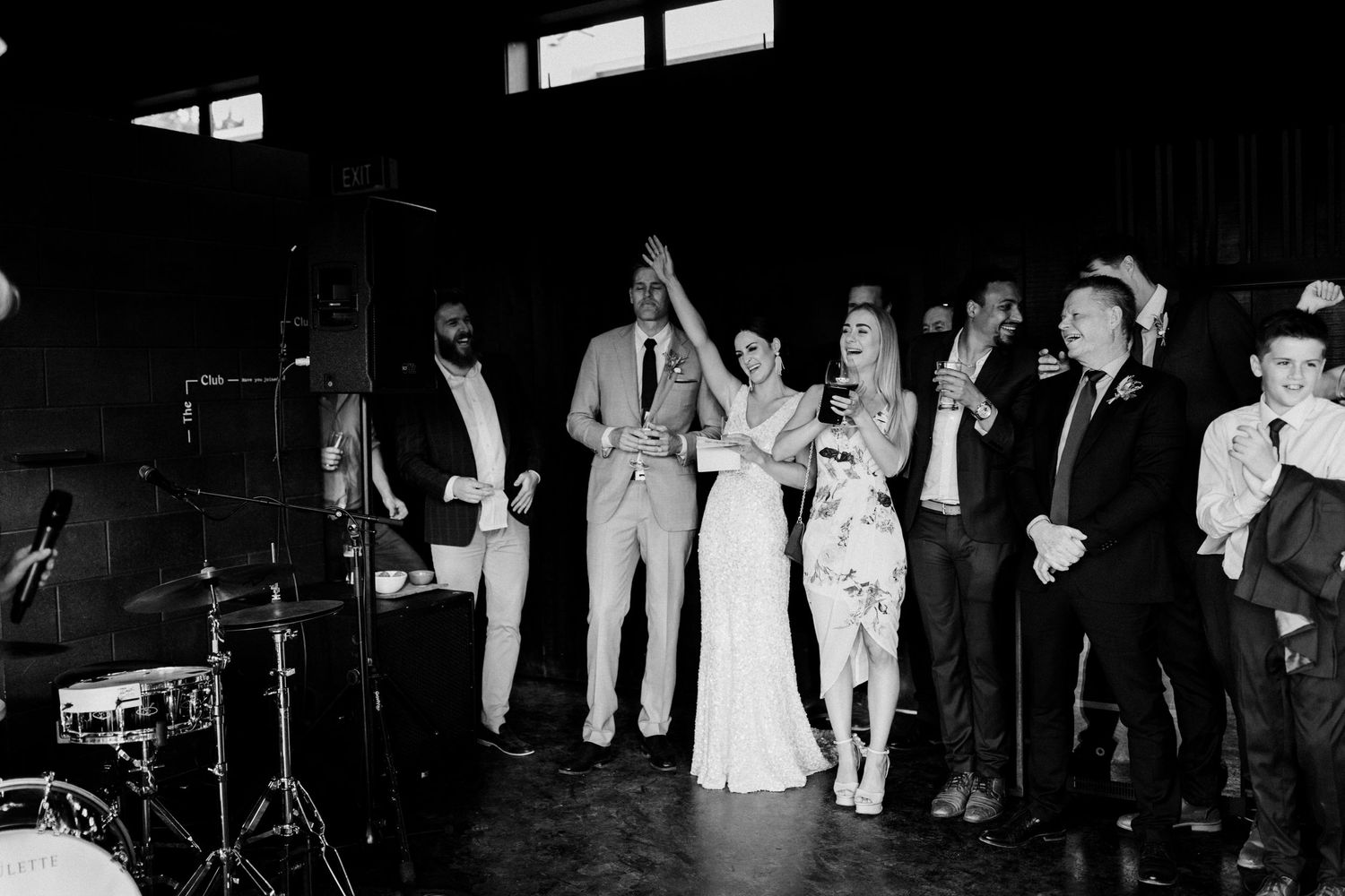 Black and white photo of wedding reception with band setup and celebrating guests.