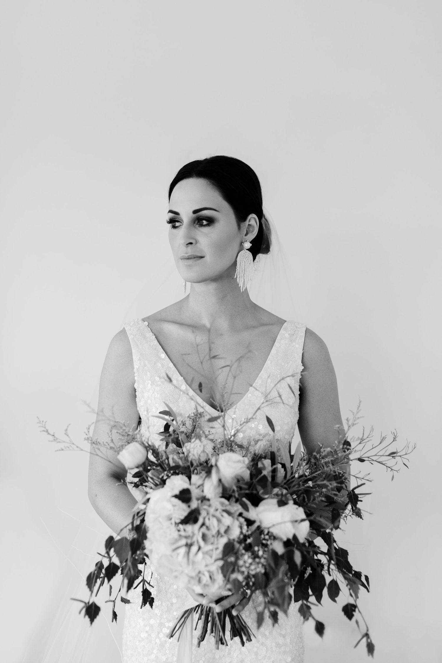 Black and white bridal portrait with natural bouquet of mixed flowers and greenery.