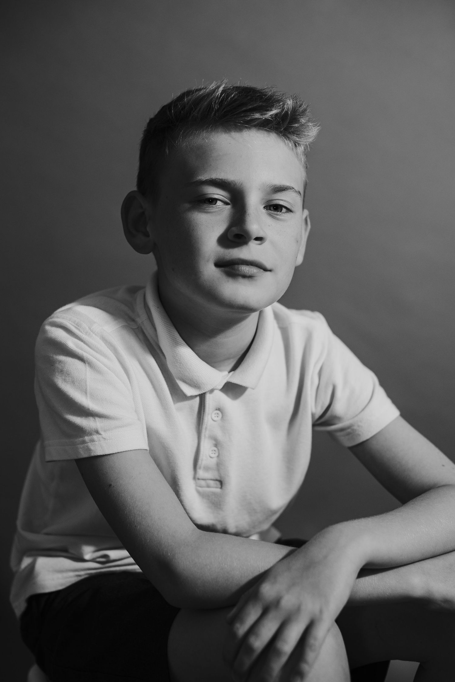 Black and white studio portrait of youth in polo shirt with contemplative expression.